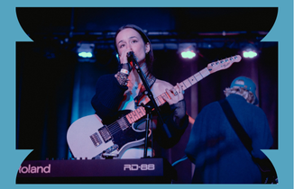 Woman with guitar and keyboard singing onstage
