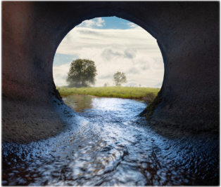 Water flowing out of a pipe into an open field