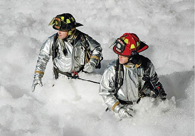 Firefighters srrounded by firefighting foam