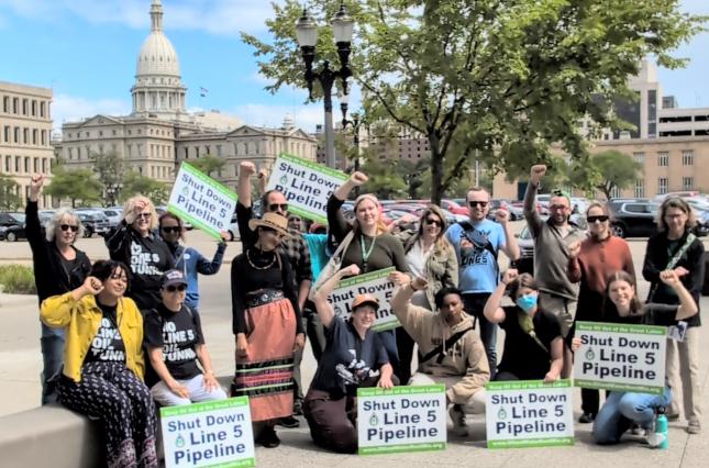 Outside the Michigan capitol building with Shut Down Line 5 Pipeline signs