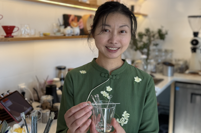 Cafe owner showing off reusable coffee cup and stirrer