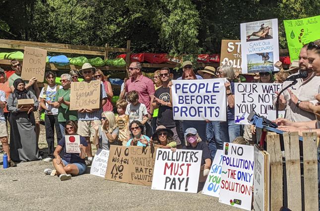 Polluter Pay rally with many attendees holding signs 