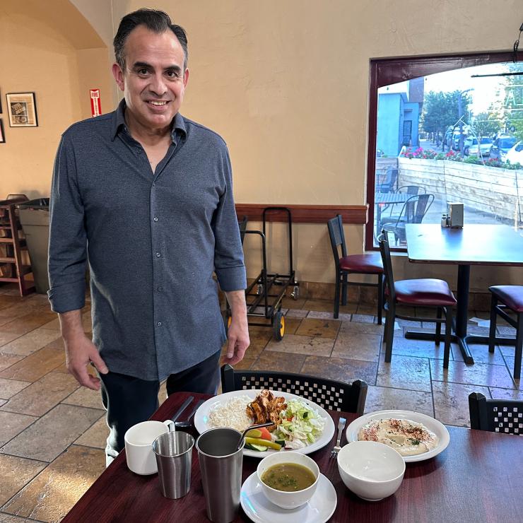 Manager of Falafal Etc posing next to a new place setting of all-reusable foodware