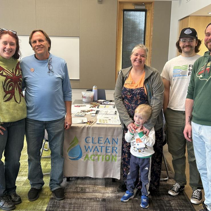 Clean Water staff and guests pose by a table with Earth Day coloring pages