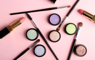 Cosmetics - lipstick, other makeup - arranged on a table. Photo credit: AfricaStudios / Shutterstock