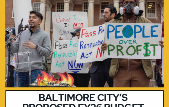 Picture of Carlos Sanchez of South Baltimore Community Land Trust speaking at a rally, with people holding signs like "Burning trash is not clean energy" and "People over profit"